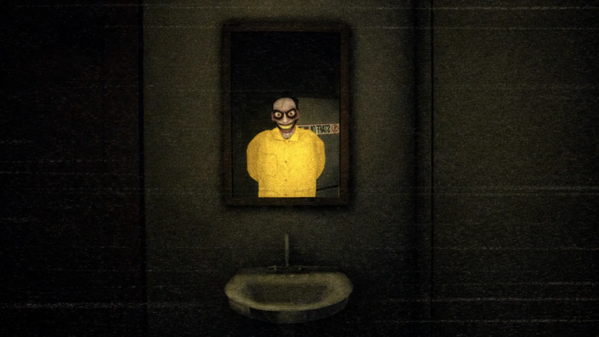 A staff member reflected in a bathroom mirror, grinning